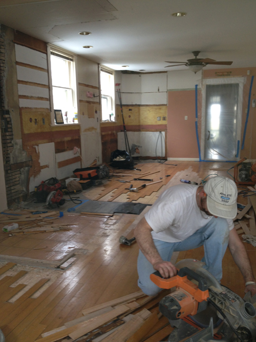 A technician from Adirondack Wood Floors installing a new hardwood floor in a living room
